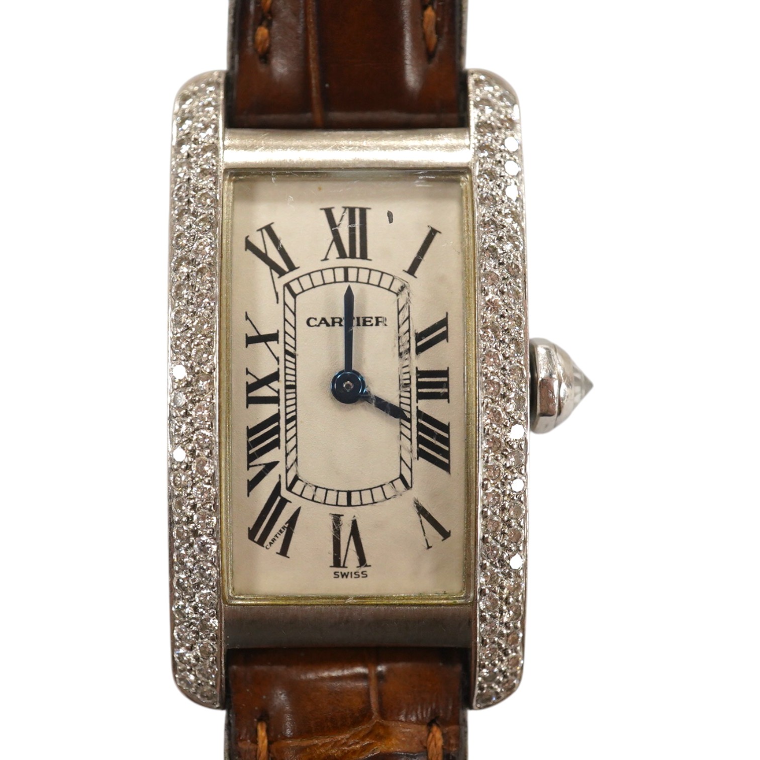 A lady's recent 18k white gold and diamond cluster set Cartier Tank Americaine quartz wrist watch, on a Cartier leather strap, case diameter 20mm, no box or papers, not currently running. Condition - fair to good.